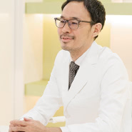 ある女性の患者さまにお会いしたのがきっかけです。医師としてキャリアをスタートさせた最初の15年間は、脳神経外科医として数多くの患者さまを治療してきました。脳の手術では1~2mmの血管を素早く丁寧につなぐなど、非常に細やかで迅速な手さばきが求められます。そのため、常に技術を磨いてきましたが、そういった医療技術をもってしても後遺症と向き合っていかなくてはならない方も少なくありませんでした。<br>そんな時、後遺症と向き合いながらもメイクで綺麗になり、自然と笑顔を浮かべる患者さまの姿を目の当たりにし、女性にとって美しくなるということは、生きていく上で大きな糧になるのだと実感しました。こうした経験を経て、人を美し、笑顔にすることのできる美容医療に興味を持つようになったのです。